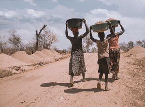 Three woman carrying water on their heads in the desert