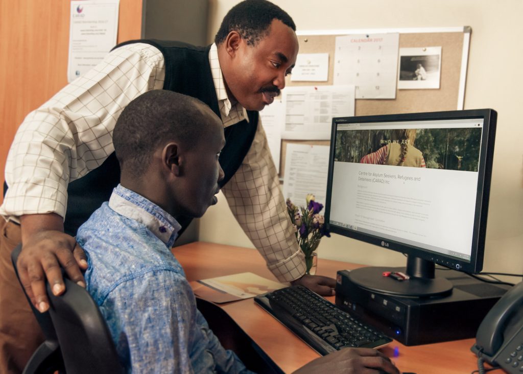 Men helping other man to use the computer