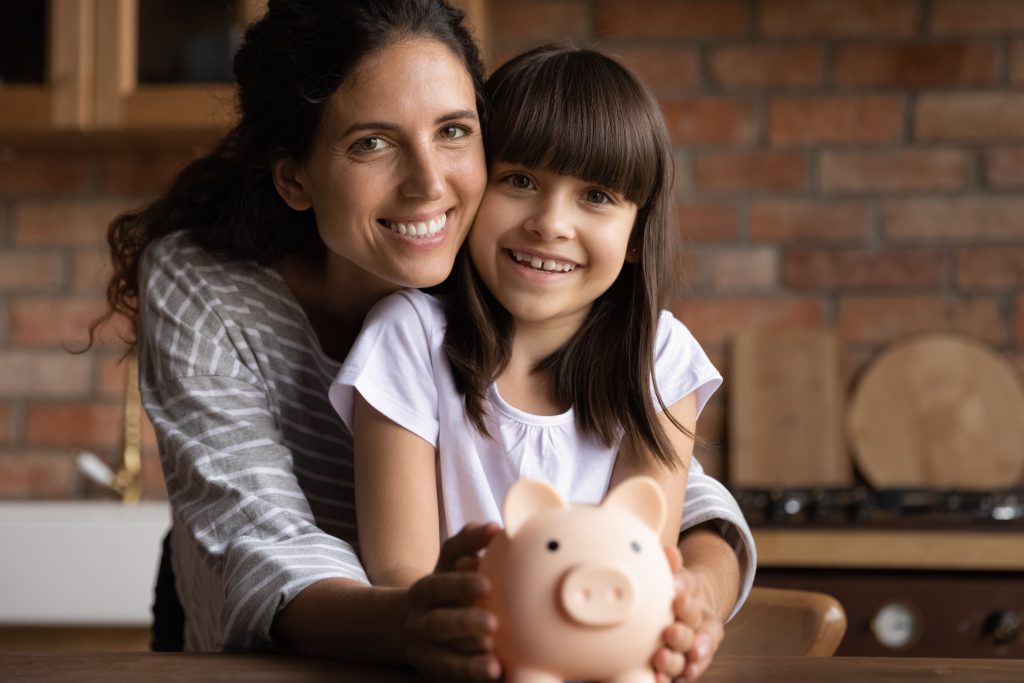 Mother and daughter holding a pig bank