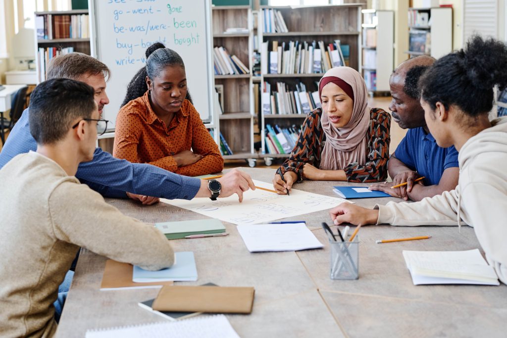 A group of multicultural people talking to each other while studying in a table